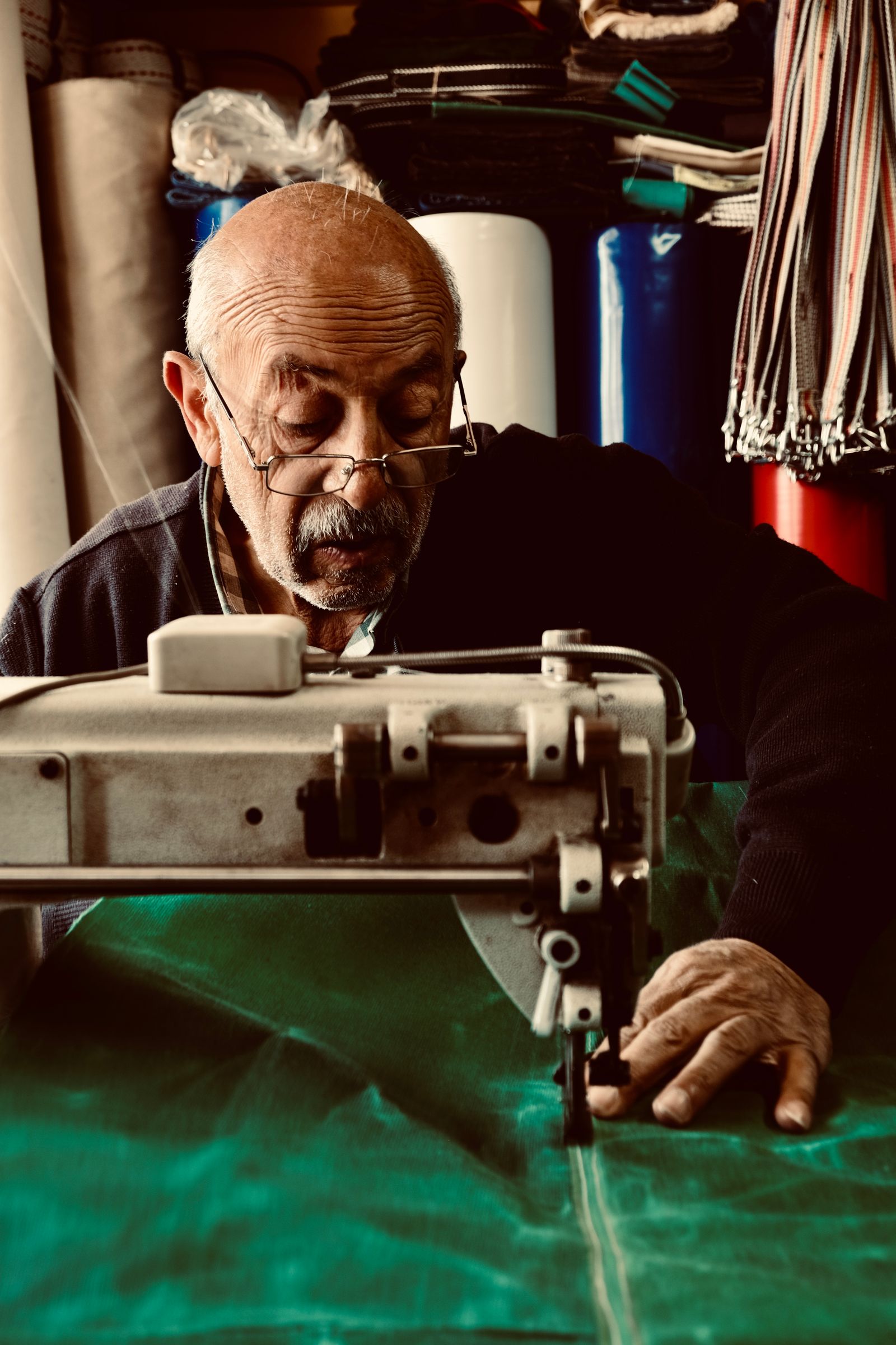 Estofador a coser tecido na máquina entre rolos de tecido